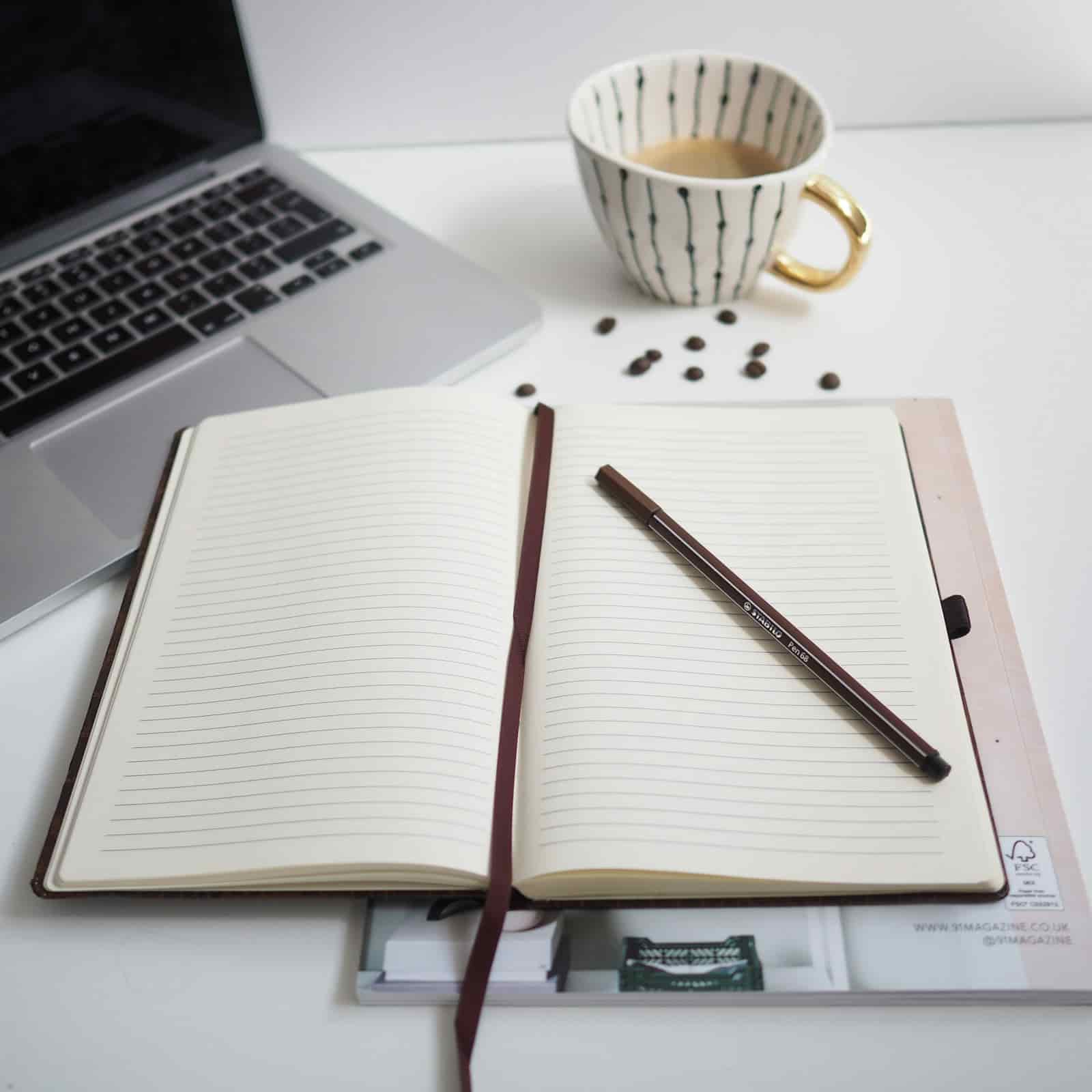 Travel advisor planning repeatable business systems in a notebook beside a laptop