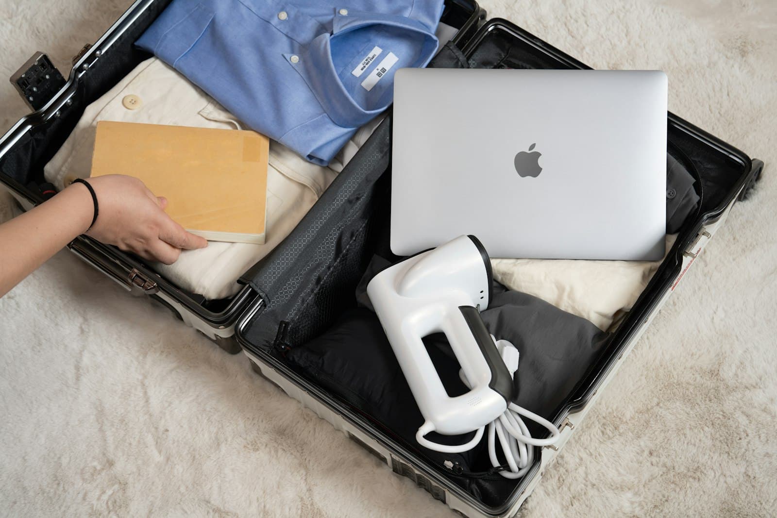 An open suitcase packed with a laptop and travel items, the kind of pre-travel document delivery a good automation layer handles on its own An open suitcase packed with a laptop and travel items, the kind of pre-travel document delivery a good automation layer handles on its own