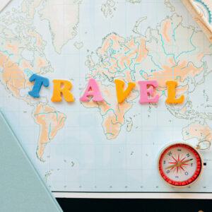 Colorful travel planning flat lay featuring a world map and compass for trip planning services.