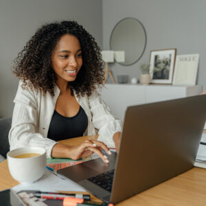 a trvavel agent facing her laptop, smiling as she gets all the proper coaching and resources from the community about lead generation