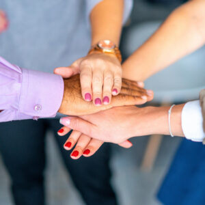 Hands of diverse travel professionals stacked in unity, symbolizing collaboration and teamwork in trip planning services.