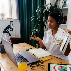 "Woman recording a podcast for lead generation, using a microphone and laptop during a virtual meeting"